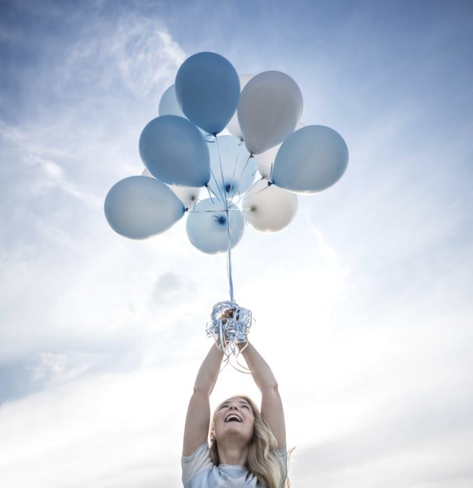 Woman holding a bunch of helium balloons outdoors